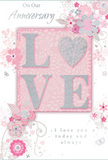 This anniversary card is presented in an intimate close-up, revealing details that make it feel like a delicate floral arrangement translated into print for a couple celebrating in Hackney. Dominating the centre is the word LOVE, each letter raised in embossed relief and lavishly dusted with fine blush-pink and pearly white glitter, with a subtle edging of silver that lends a soft, romantic sparkle, similar to dew catching early morning light on petals in a local garden. The texture of the lettering appears soft yet pronounced, suggesting a satisfying tactile experience as fingers move across its curves. Flowing outward from this central word, a loose garland of stylised flowers, scrolling stems, and curling leaves travels across the card in a gentle arc. The blooms are drawn with thin, elegant lines in gentle pinks, pale whites, and smoky silvers, some petals gently shaded, others implied with minimal strokes, creating a sense of breath and movement as if caught in a light breeze on Hackney Downs. The background is a smooth, powdery pink, subtly varied in tone so it feels luminous rather than flat, framing the artwork with a calm, romantic glow. Positioned amidst the florals is a simple, heartfelt anniversary message in a flowing script, legible and graceful, echoing the quiet sincerity of a hand-written note nestled into a bouquet. The overall impression is one of tender celebration and enduring affection-a keepsake that captures the soft, lingering feeling of love shared over many years in the heart of Hackney.